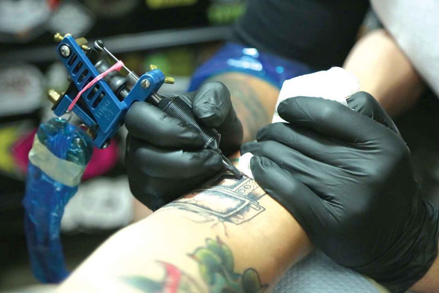 Tattoo artist Mitchell Dean details new ink for a patron, three television sets stacked on top of each other.