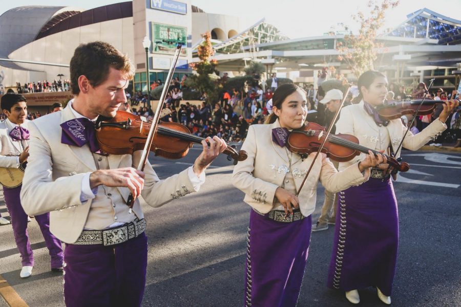 Mariachis plays their instruments as they walk through the parade. 